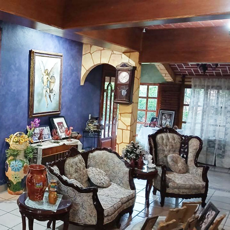 Interior living room of country home house for sale real estate in San Francisco Lachigoló with purple walls, wooden beams on ceiling and stone and brick arches with good natural light through windows and a door with glass windows