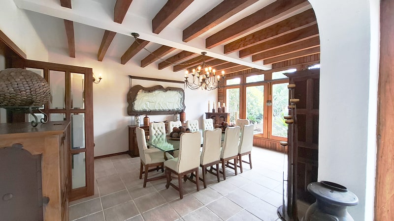 Formal dining room seating ten, with beamed ceiling and garden windows — villa in San Felipe del Agua, Oaxaca