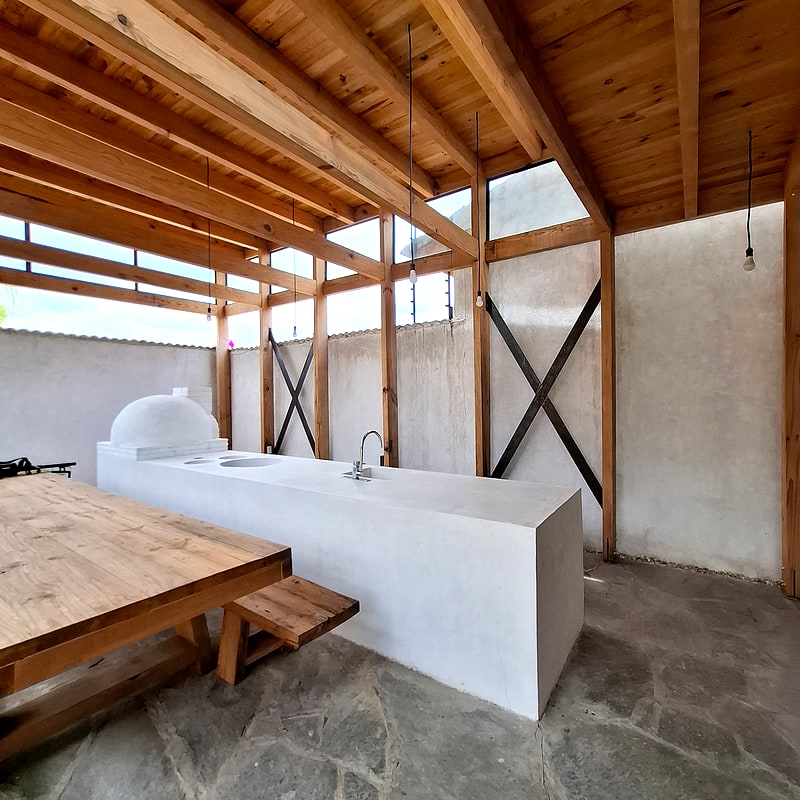 Guest house patio kitchen with wood-fired oven, comal and long beer-hall table — Oaxaca, Mexico