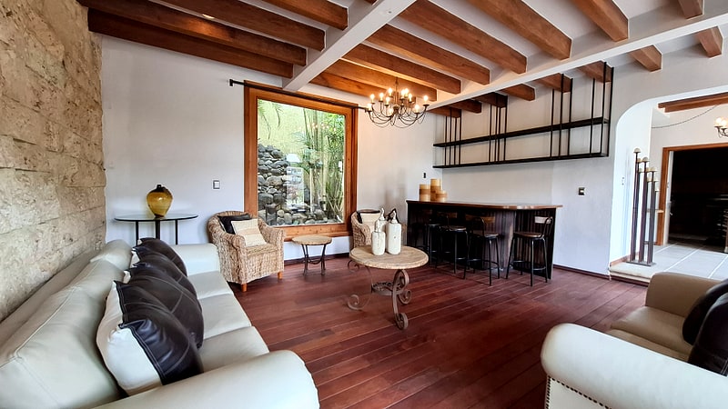 Living room with natural stone wall, leather sofas and bar — luxury villa in Oaxaca, Mexico