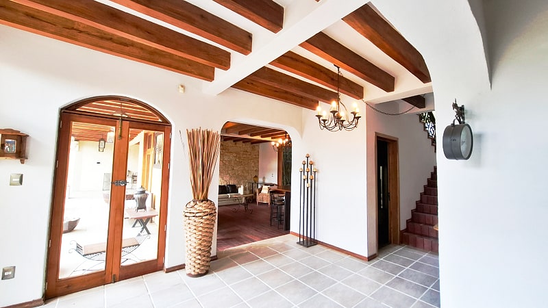 Entry foyer with arched wood door, beamed ceiling and staircase — luxury home for sale in San Felipe del Agua