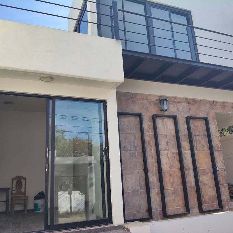 Exterior view of blancony and sliding glass doors with lots of natural light two story Santa Rosa Bugambilias house home real estate for sale in Oaxaca, Mexico