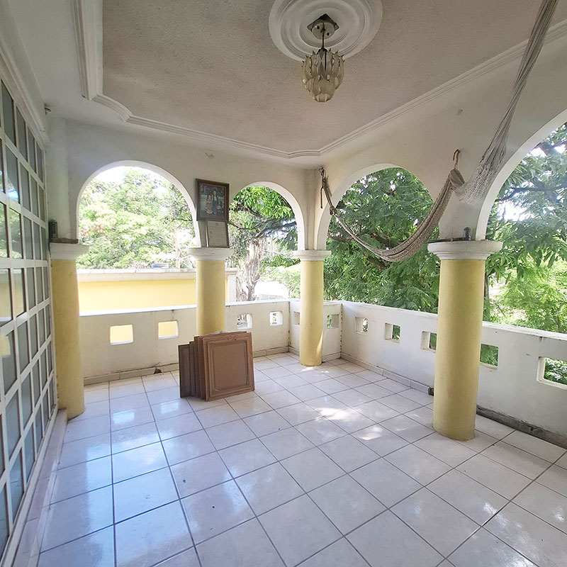 Second floor balcony terrace on master bedroom overlooking unpaved road with mango trees with four yellow columns with arches and floor to ceiling glass french door in house home for sale casa en venta in San Antonio de la Cal Oaxaca, Mexico real estate