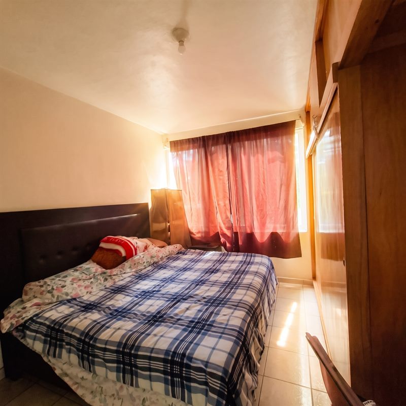 Second bedroom with fitted wooden wardrobe and tile floor in a two story home for sale near Simbolos Patrios, Oaxaca
