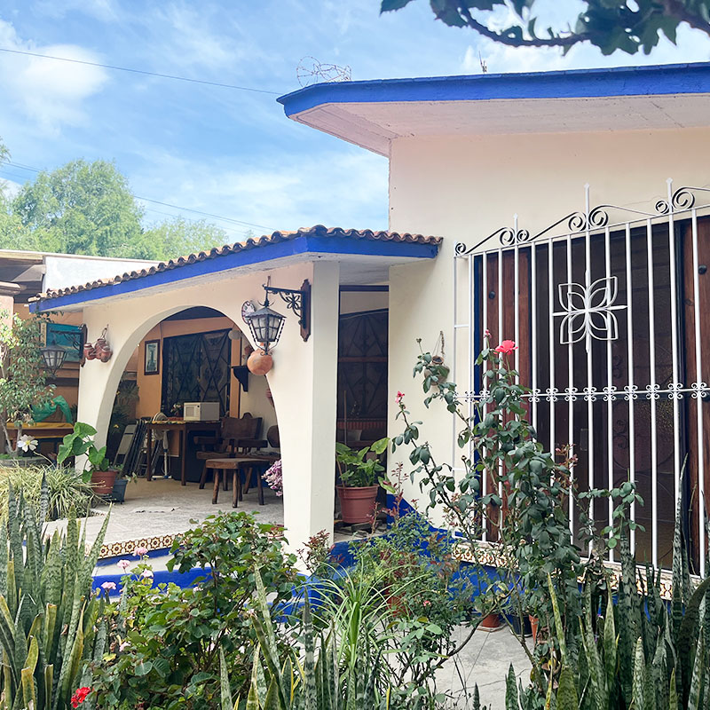 Cream facade with cobalt blue trim and arched covered porch of single floor casa en venta with two apartments and storefront in El Tule Santa Maria del Tule Oaxaca, Mexico real estate