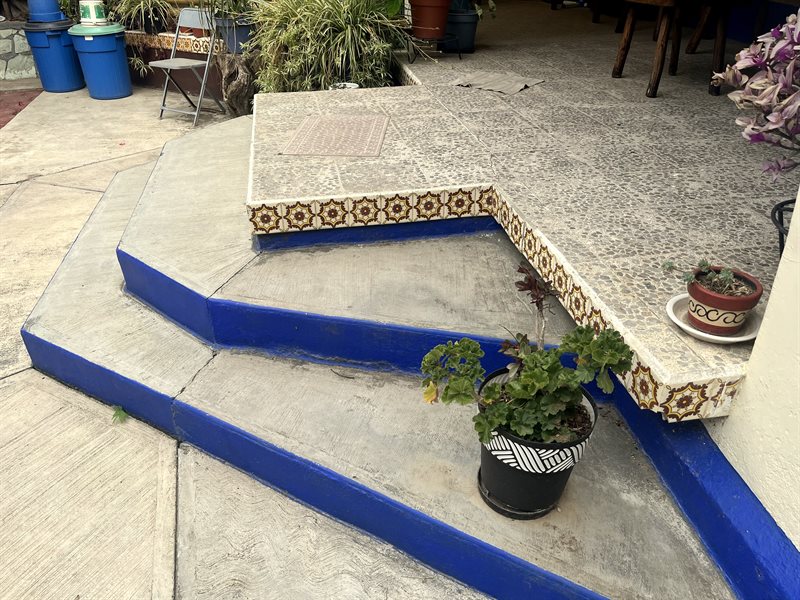 Front patio steps with talavera tile edging and blue trim leading up to the porch of El Tule property for sale
