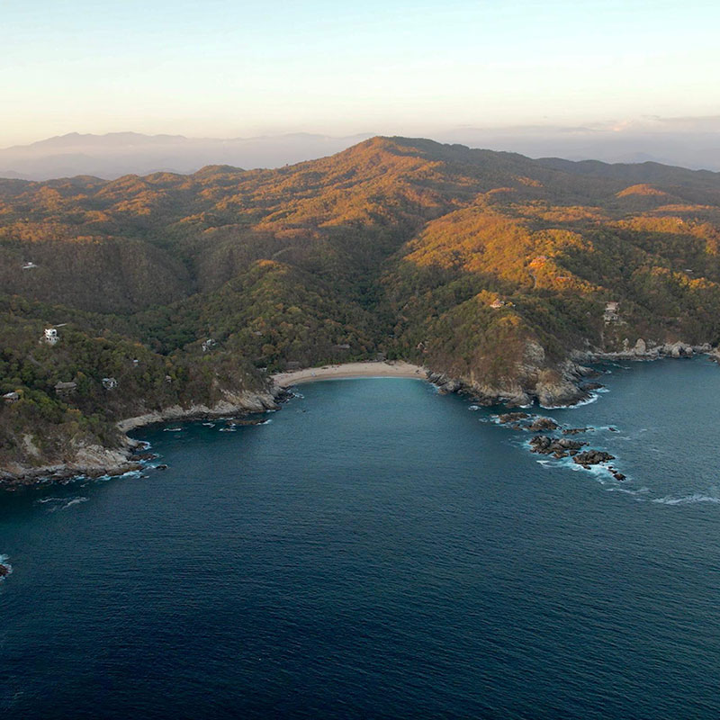 Vue aérienne du terrain en bord de mer à Playa La Boquilla sur la côte Pacifique d'Oaxaca, Mexique, entouré de collines boisées