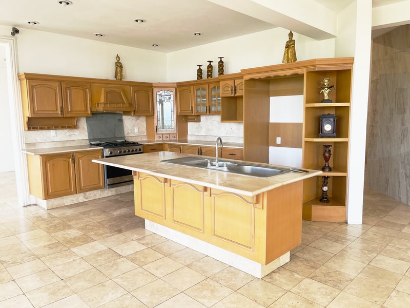 Kitchen with island, wooden cabinets and six burner gas range in a Colonia Estrella house for rent in Oaxaca